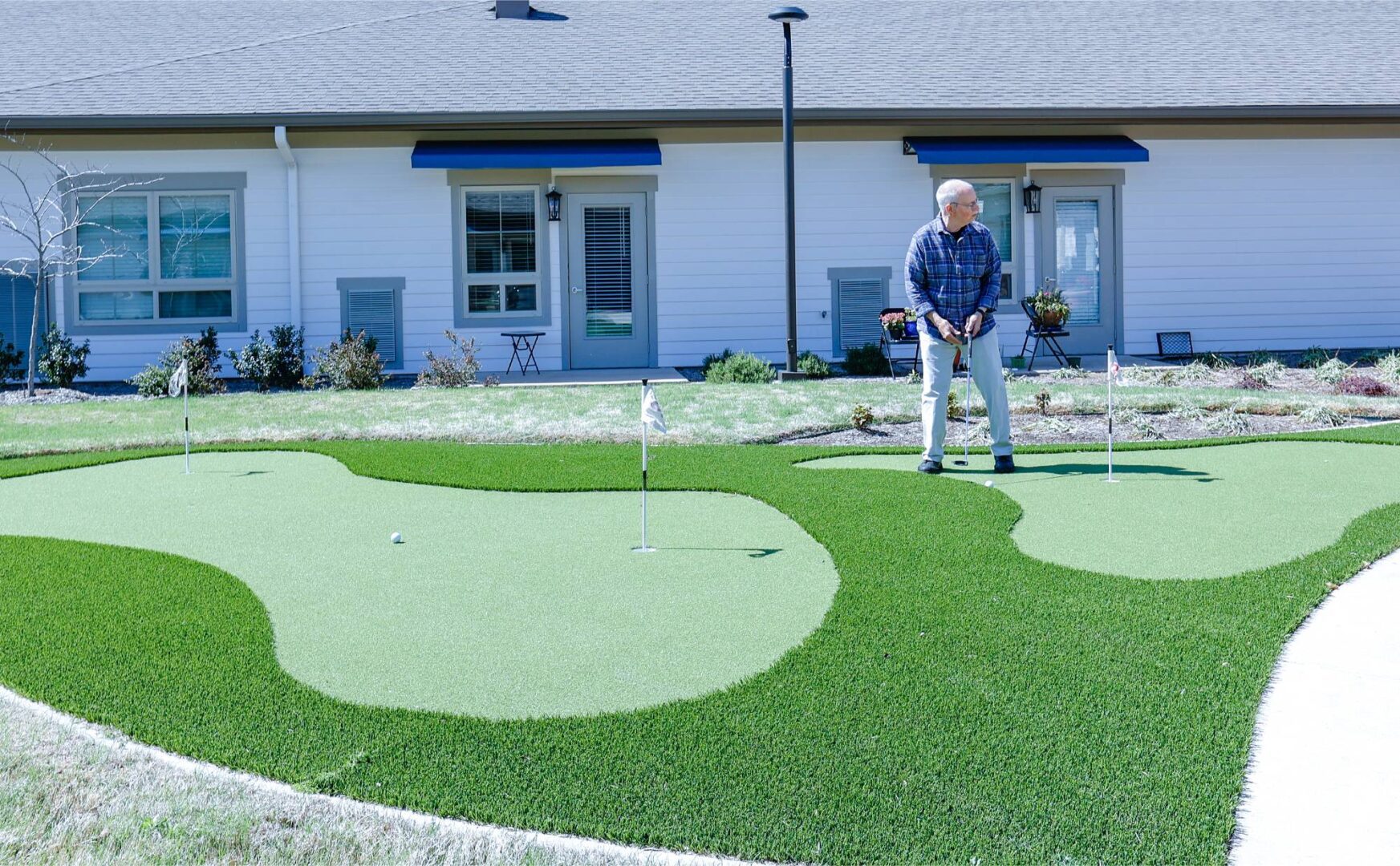 A man playing golf in the backyard of his home.