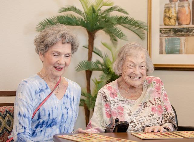 Two women sitting at a table with a phone.