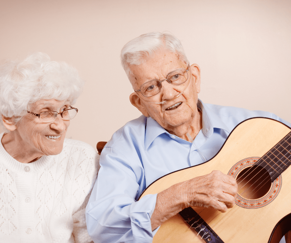 An older man and woman playing a guitar.