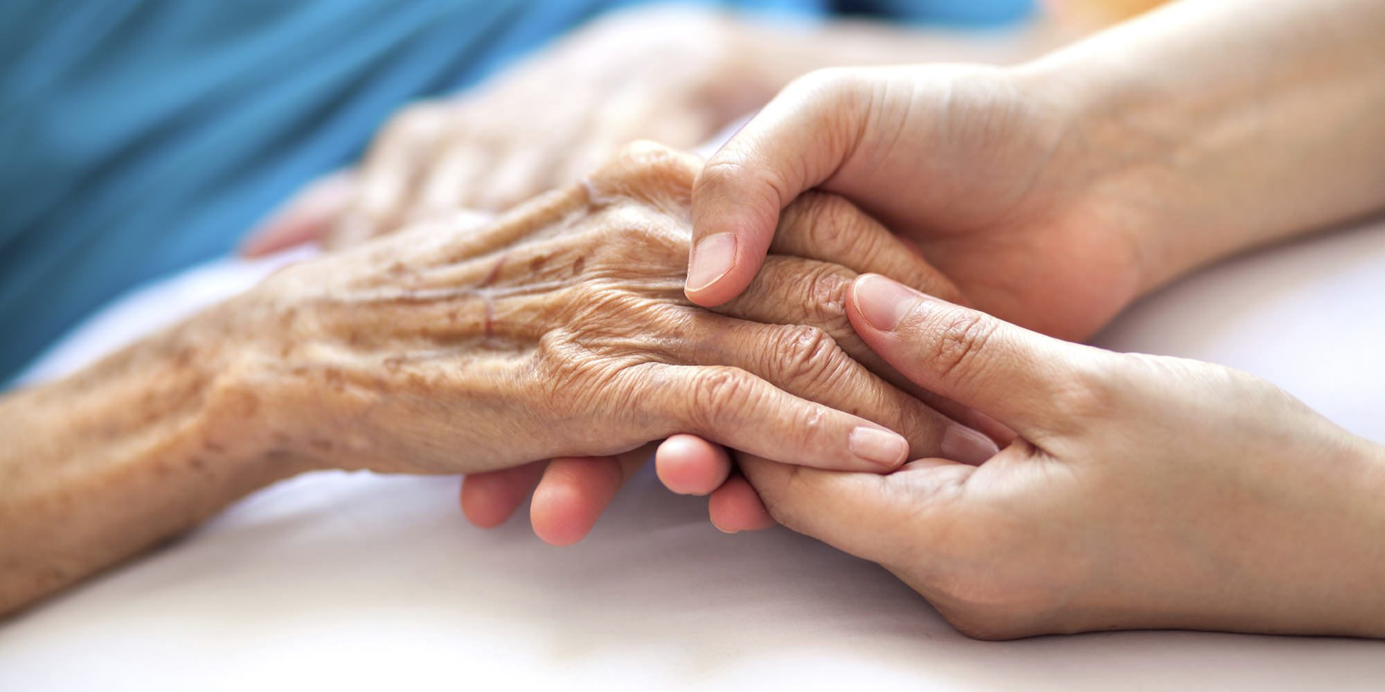 A person holding an elderly hand over another 's arm.
