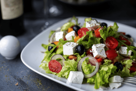 A plate of salad with feta cheese and tomatoes.