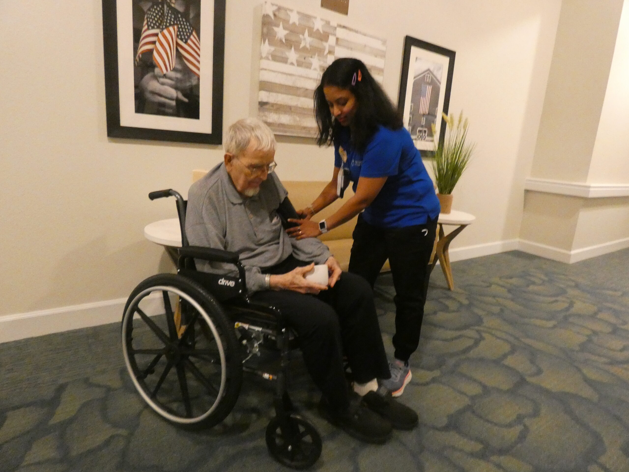 A woman helping an elderly man in a wheelchair.