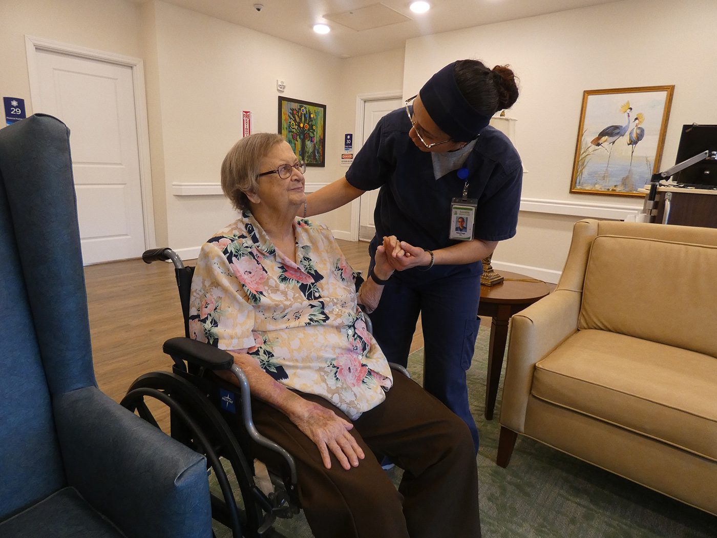 A nurse is helping an elderly woman in a wheelchair.