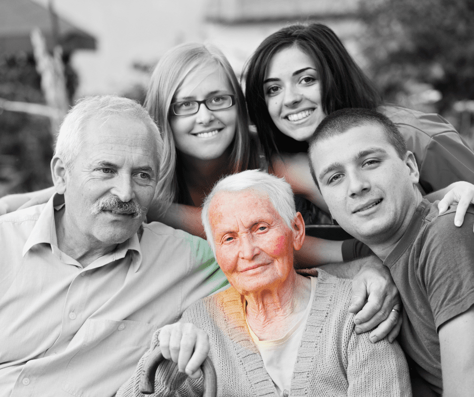 A family posing for a picture with an old woman.