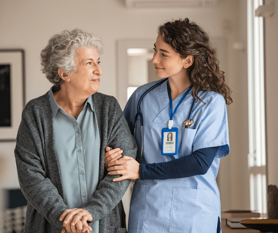 A nurse and an older woman holding hands.