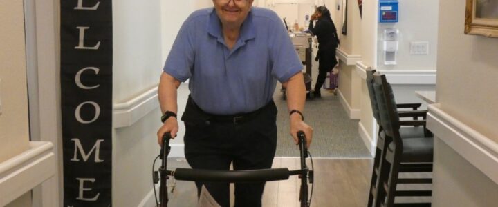 A resident walks down the hallways using a walker to support his gait.