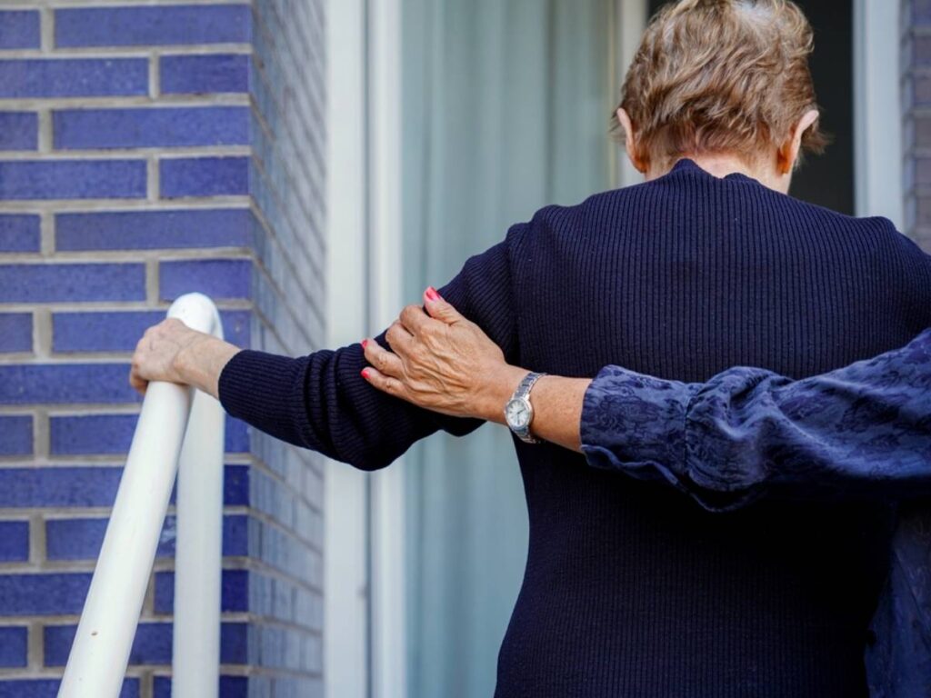 A memory care community team member walking into a building with an eloped patient.